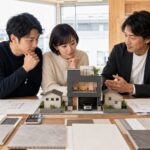 狭小住宅の模型を前にハウスメーカー選びを相談する日本人夫婦と設計士